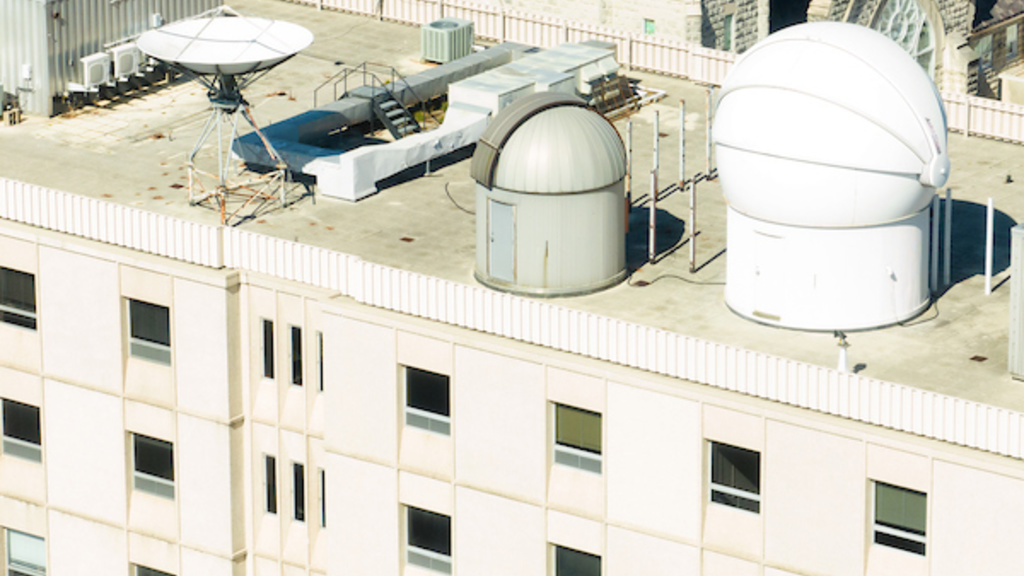 An aerial photograph of the rooftop telescopes on Van Allen Hall